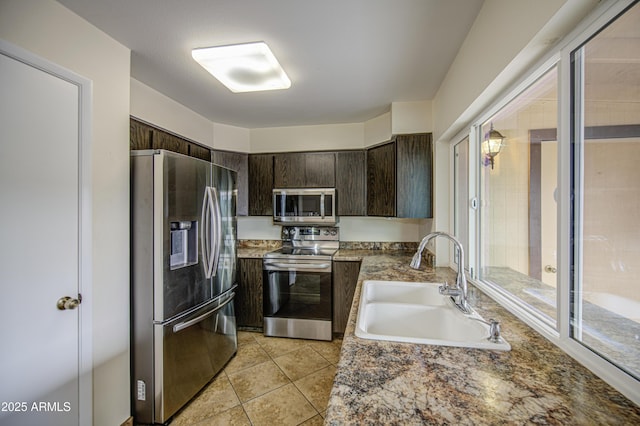 kitchen with dark brown cabinets, appliances with stainless steel finishes, a sink, and light tile patterned floors
