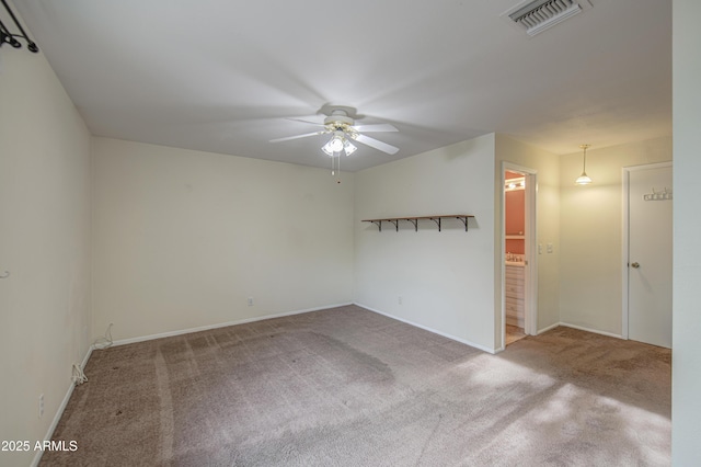 carpeted empty room with ceiling fan, visible vents, and baseboards