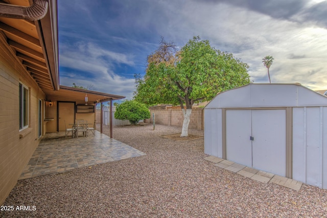 view of yard with a fenced backyard, a storage unit, a patio, and an outdoor structure