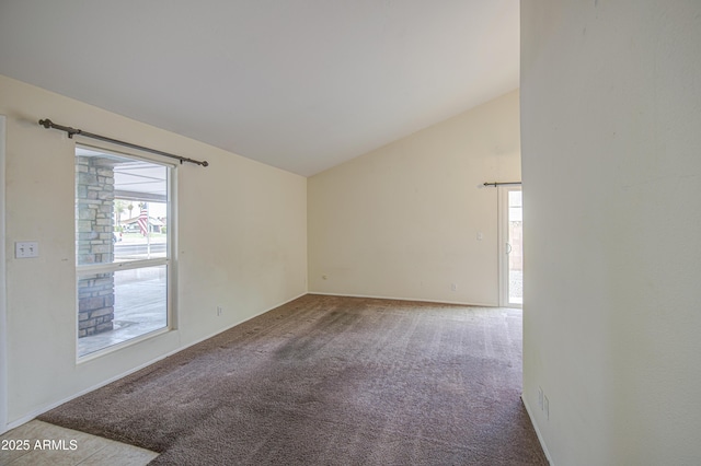 carpeted spare room featuring baseboards and vaulted ceiling