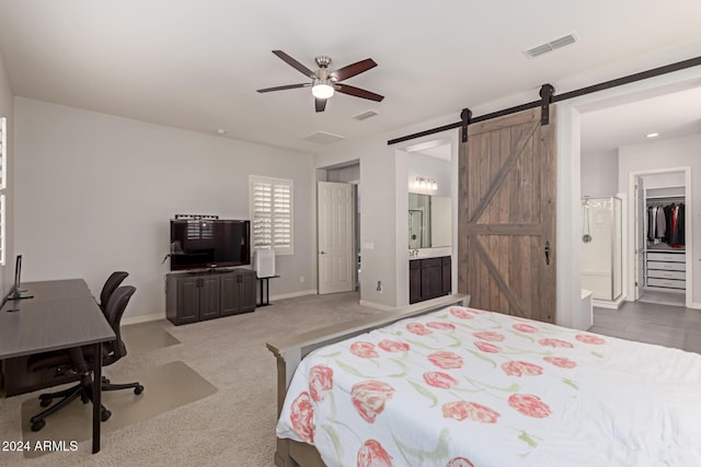 carpeted bedroom featuring ensuite bath, ceiling fan, a barn door, a walk in closet, and a closet