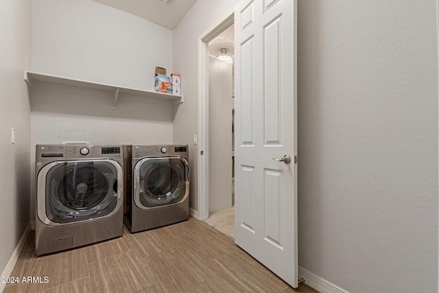 clothes washing area with washer and clothes dryer and light wood-type flooring