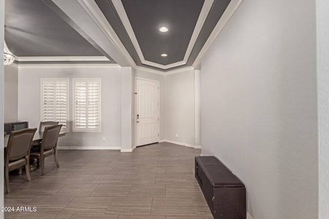 entryway with ornamental molding and a tray ceiling