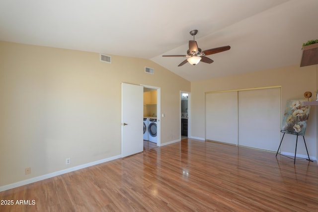 unfurnished bedroom with washing machine and clothes dryer, ceiling fan, hardwood / wood-style floors, vaulted ceiling, and a closet