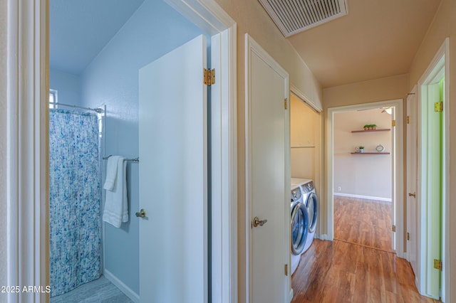 interior space featuring wood-type flooring, independent washer and dryer, and walk in shower