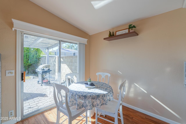 dining space featuring hardwood / wood-style flooring and vaulted ceiling