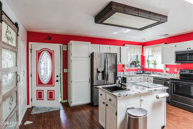 kitchen with dark wood-type flooring, stainless steel appliances, sink, a center island, and white cabinets