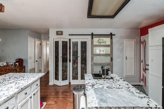 kitchen with sink, white cabinets, dark hardwood / wood-style floors, and a barn door