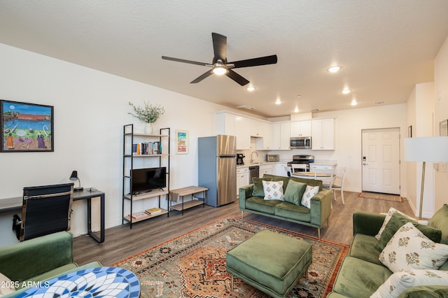 living room with hardwood / wood-style flooring, ceiling fan, sink, and a textured ceiling