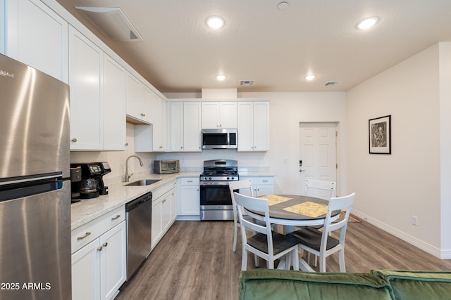 kitchen featuring white cabinetry, sink, light stone counters, and appliances with stainless steel finishes