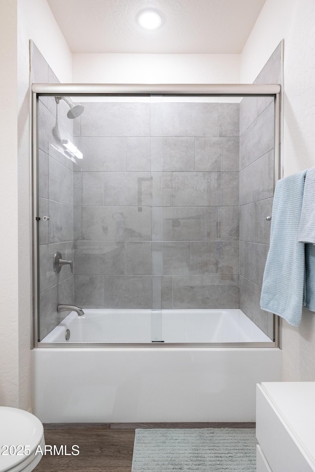 full bathroom featuring hardwood / wood-style flooring, vanity, toilet, and combined bath / shower with glass door