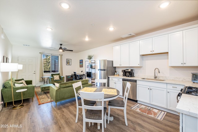 kitchen with sink, appliances with stainless steel finishes, hardwood / wood-style flooring, ceiling fan, and white cabinets