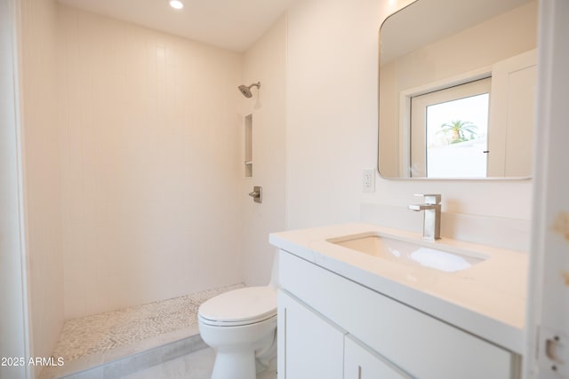 bathroom featuring vanity, toilet, and a tile shower