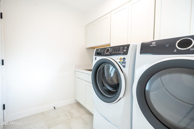 clothes washing area featuring cabinets and washing machine and clothes dryer