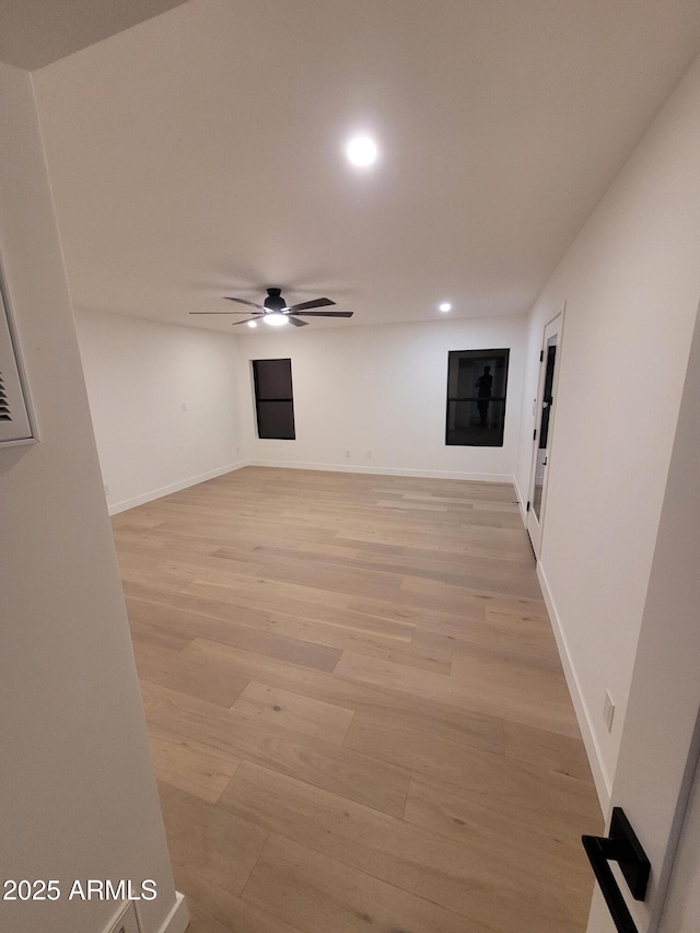 empty room with ceiling fan and light hardwood / wood-style flooring