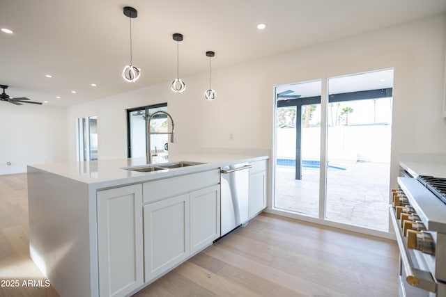 kitchen with sink, white cabinetry, hanging light fixtures, stainless steel appliances, and light hardwood / wood-style floors