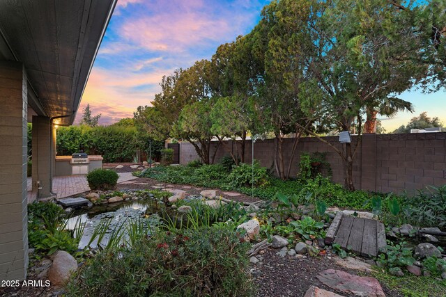 315 E Marlette Ave, Phoenix, AZ 85012 - yard at dusk featuring an outdoor kitchen, a fenced backyard, and a small pond