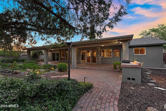 315 E Marlette Ave, Phoenix, AZ 85012 - back of house at dusk featuring brick siding, roof with shingles, and a patio