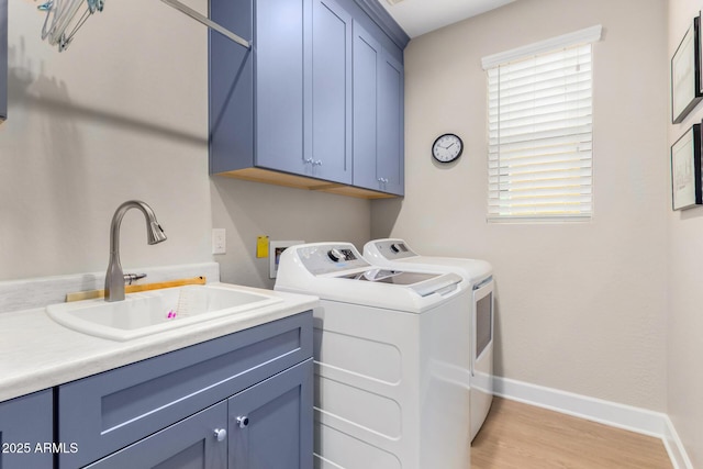 laundry room featuring cabinets, washing machine and clothes dryer, light hardwood / wood-style floors, and sink