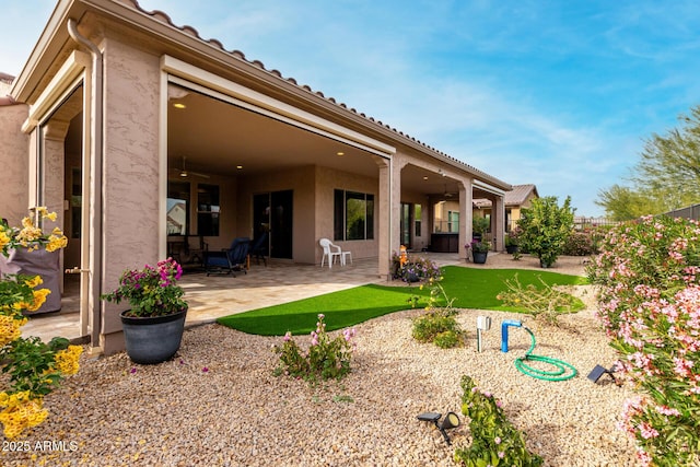 rear view of house featuring ceiling fan and a patio area