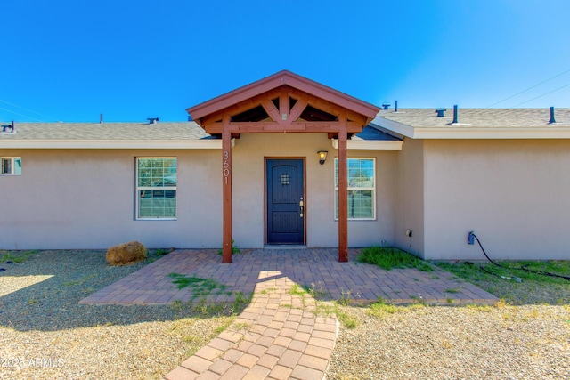 property entrance featuring roof with shingles and stucco siding