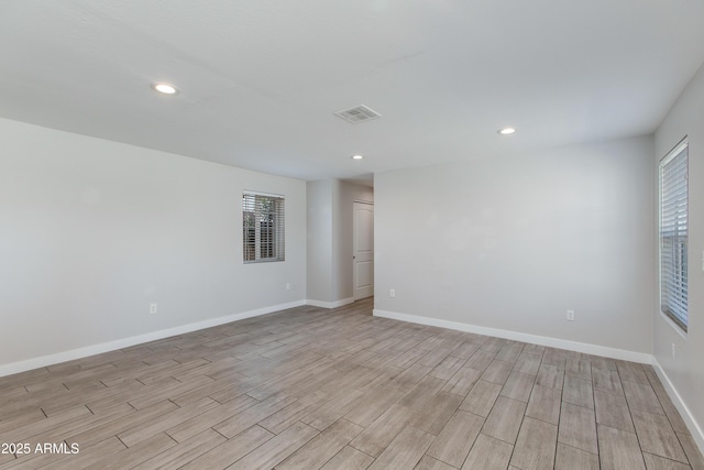 empty room featuring visible vents, a healthy amount of sunlight, and baseboards