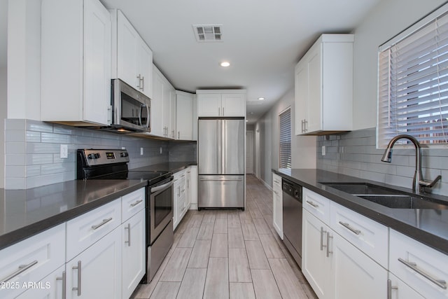 kitchen featuring visible vents, a sink, backsplash, appliances with stainless steel finishes, and white cabinets