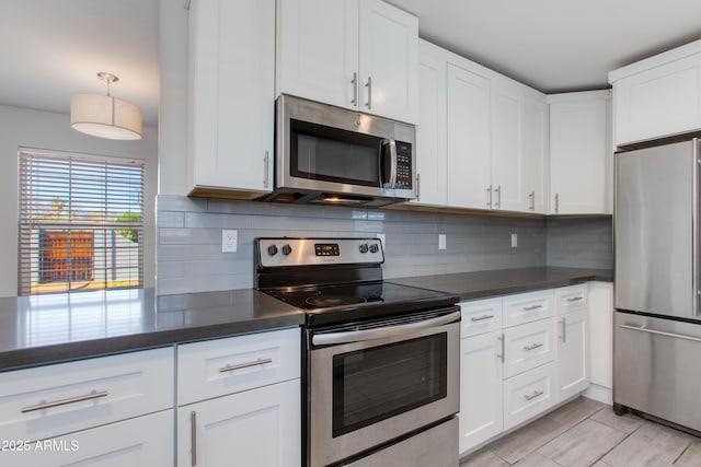 kitchen with dark countertops, appliances with stainless steel finishes, and white cabinetry