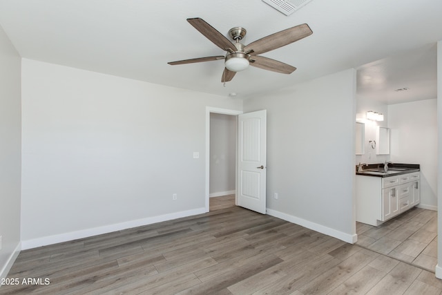 interior space with light wood-style flooring, baseboards, visible vents, and a sink