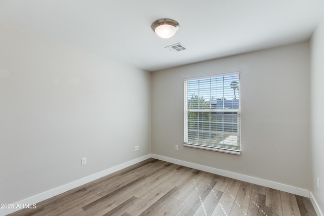 unfurnished room featuring wood finished floors, visible vents, and baseboards