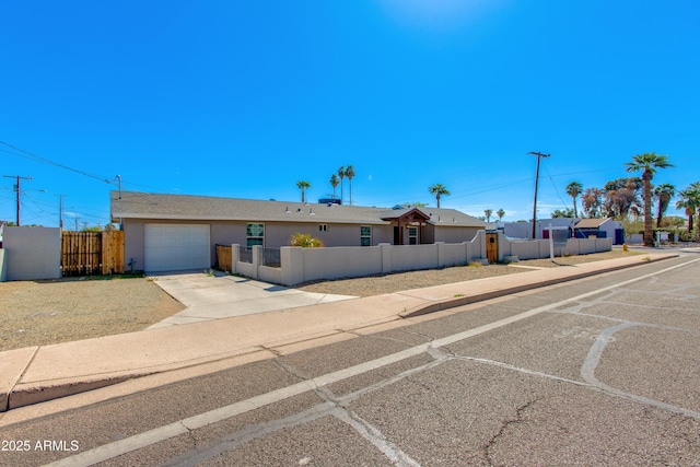 view of front facade with a fenced front yard, a garage, driveway, and stucco siding