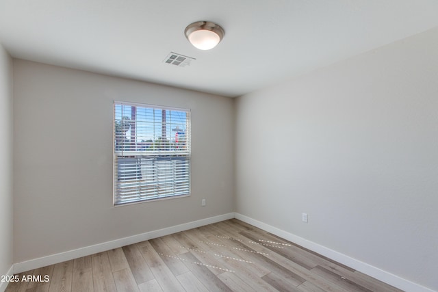 empty room featuring visible vents, baseboards, and wood finished floors