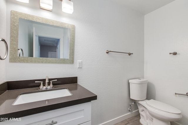 half bathroom featuring toilet, vanity, baseboards, and wood finished floors