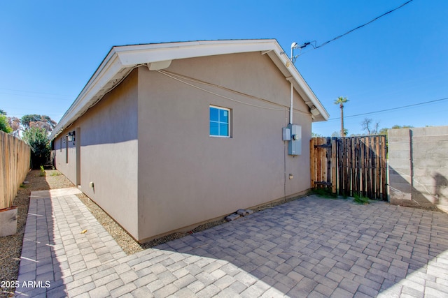 view of home's exterior featuring stucco siding, fence, and a patio area