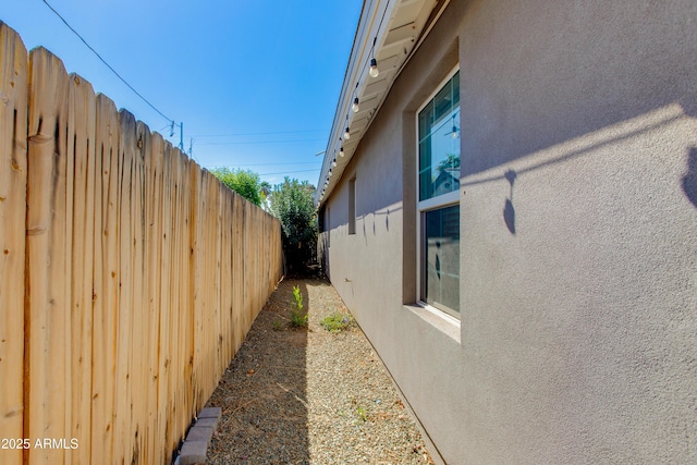 view of side of home featuring fence and stucco siding