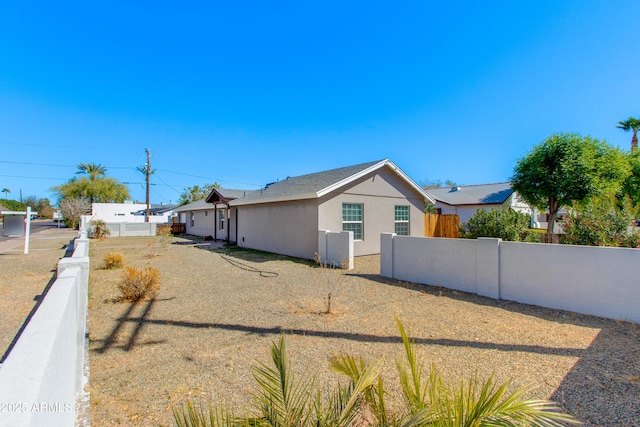 view of side of home featuring stucco siding and fence