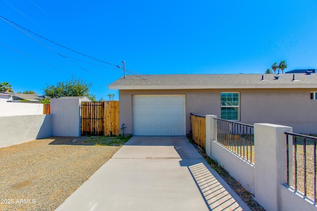 garage featuring a gate, fence, and driveway