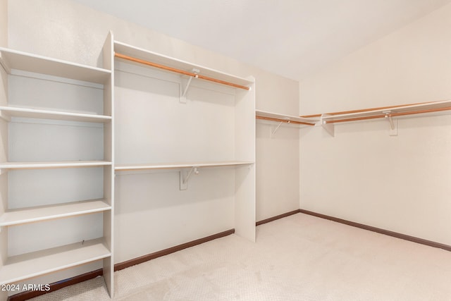 spacious closet featuring light carpet and vaulted ceiling