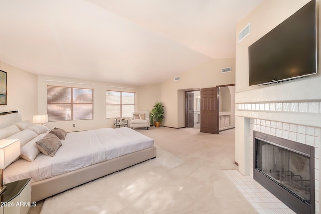 carpeted bedroom featuring a tiled fireplace and lofted ceiling