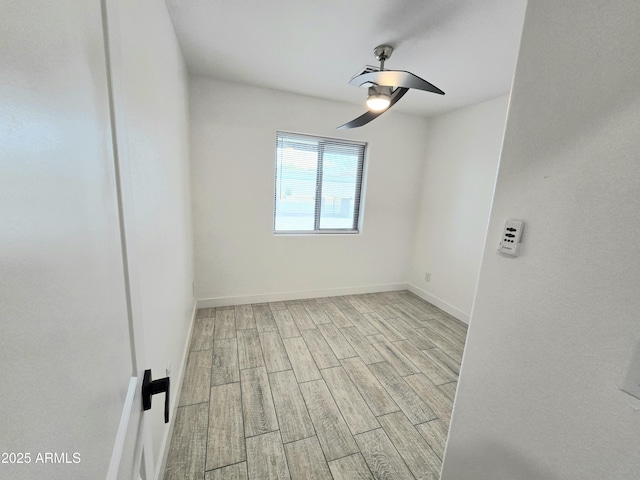 spare room featuring ceiling fan, baseboards, and wood finished floors