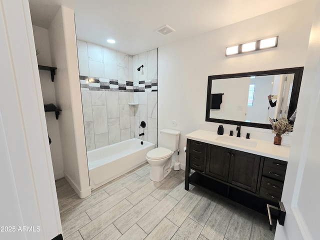 bathroom featuring visible vents, toilet, wood tiled floor, tub / shower combination, and vanity