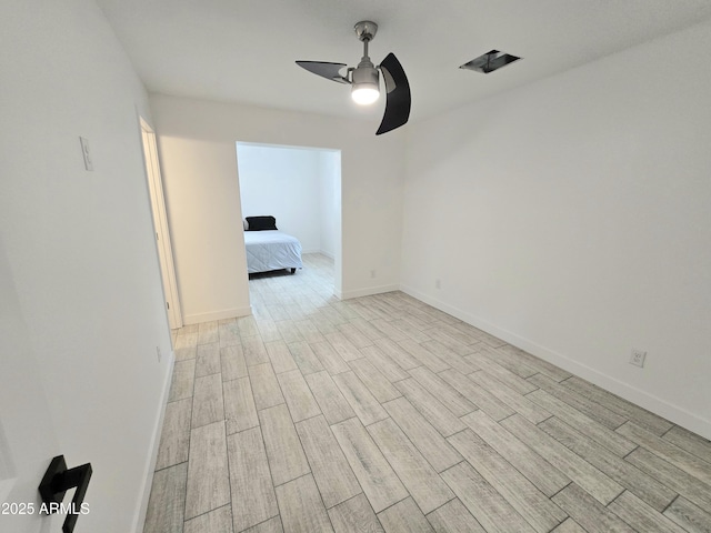 spare room with a ceiling fan, wood tiled floor, and baseboards