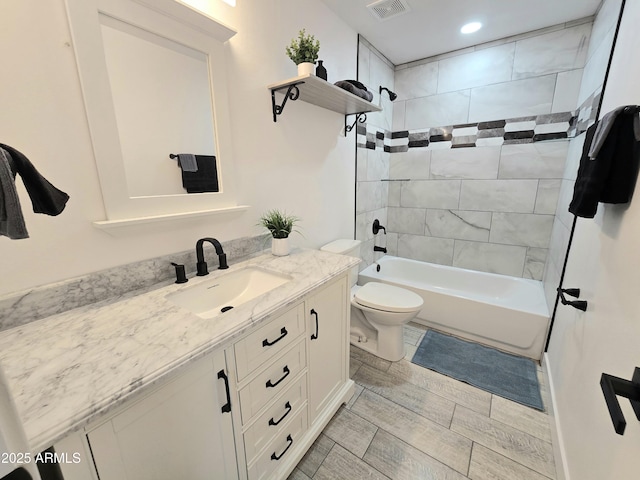 full bath with toilet, vanity, visible vents, wood tiled floor, and washtub / shower combination