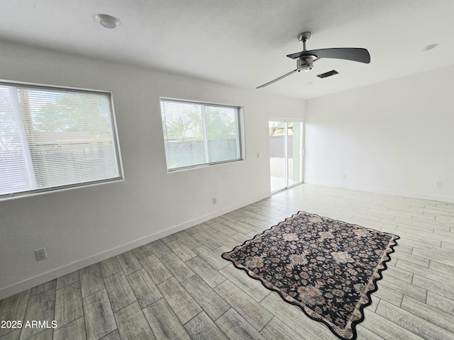 empty room with visible vents, ceiling fan, baseboards, and wood finished floors