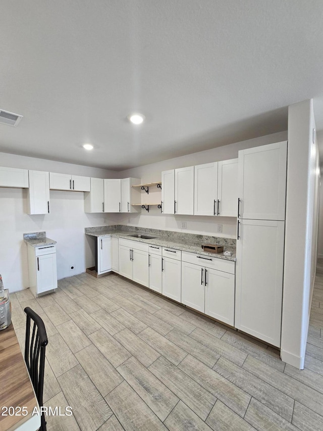 kitchen with white cabinetry, wood tiled floor, and visible vents