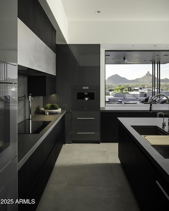 kitchen featuring range hood, wall oven, a mountain view, black electric cooktop, and sink