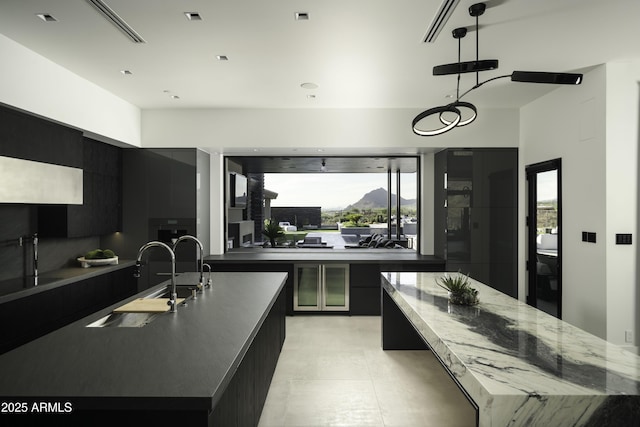 kitchen with a large island with sink, decorative light fixtures, sink, and a wealth of natural light