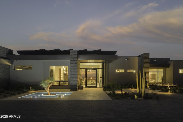 back house at dusk featuring a patio