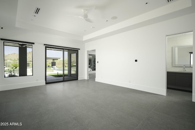 interior space with a raised ceiling, ceiling fan, and sink