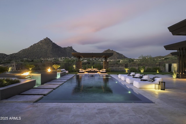 pool at dusk featuring a mountain view and a patio area